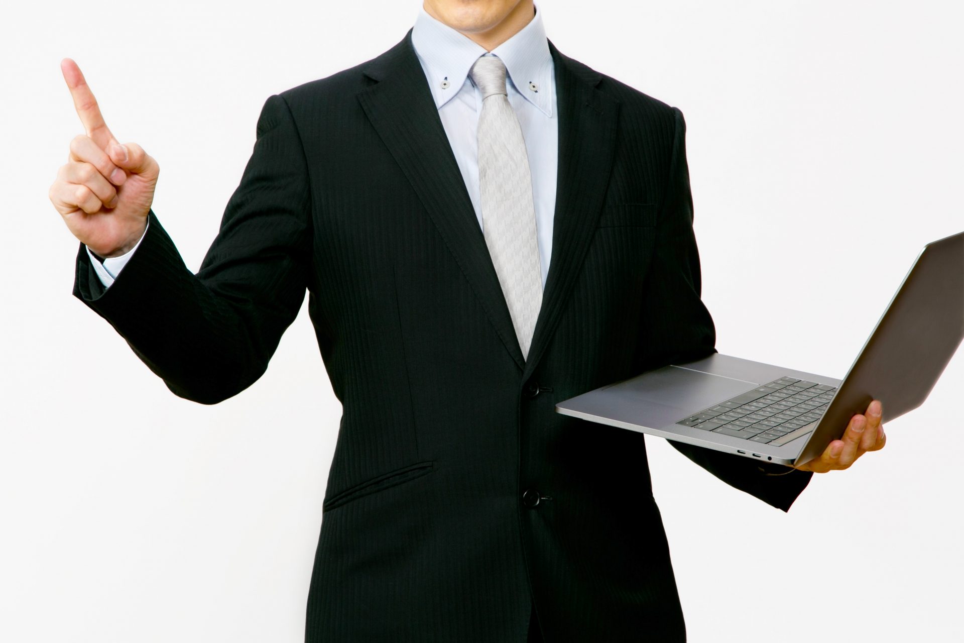 ノートパソコンを片手に持って上を指差すスーツを着た男性