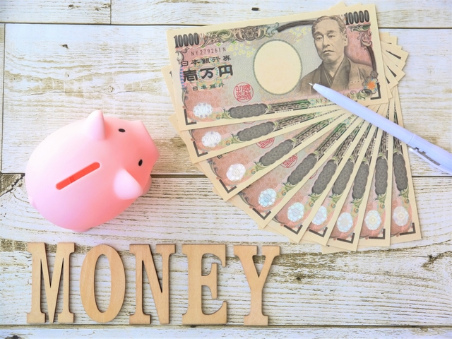 机の上に置かれた豚の貯金箱と9枚の1万円札