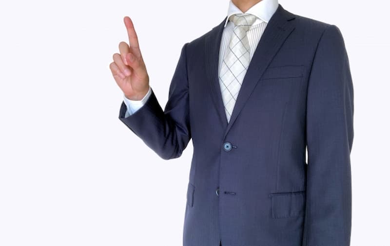 人差し指を立てるスーツの男性